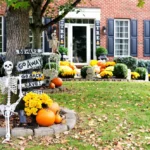A colonial brick house decorated with a skull and halloween decorations during the fall.
