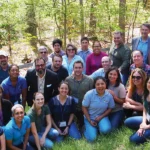 Together for Birds - a group ABC staff gathers outdoors in a forest to celebrate.