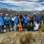 Twelve people posed with mountains in the background.